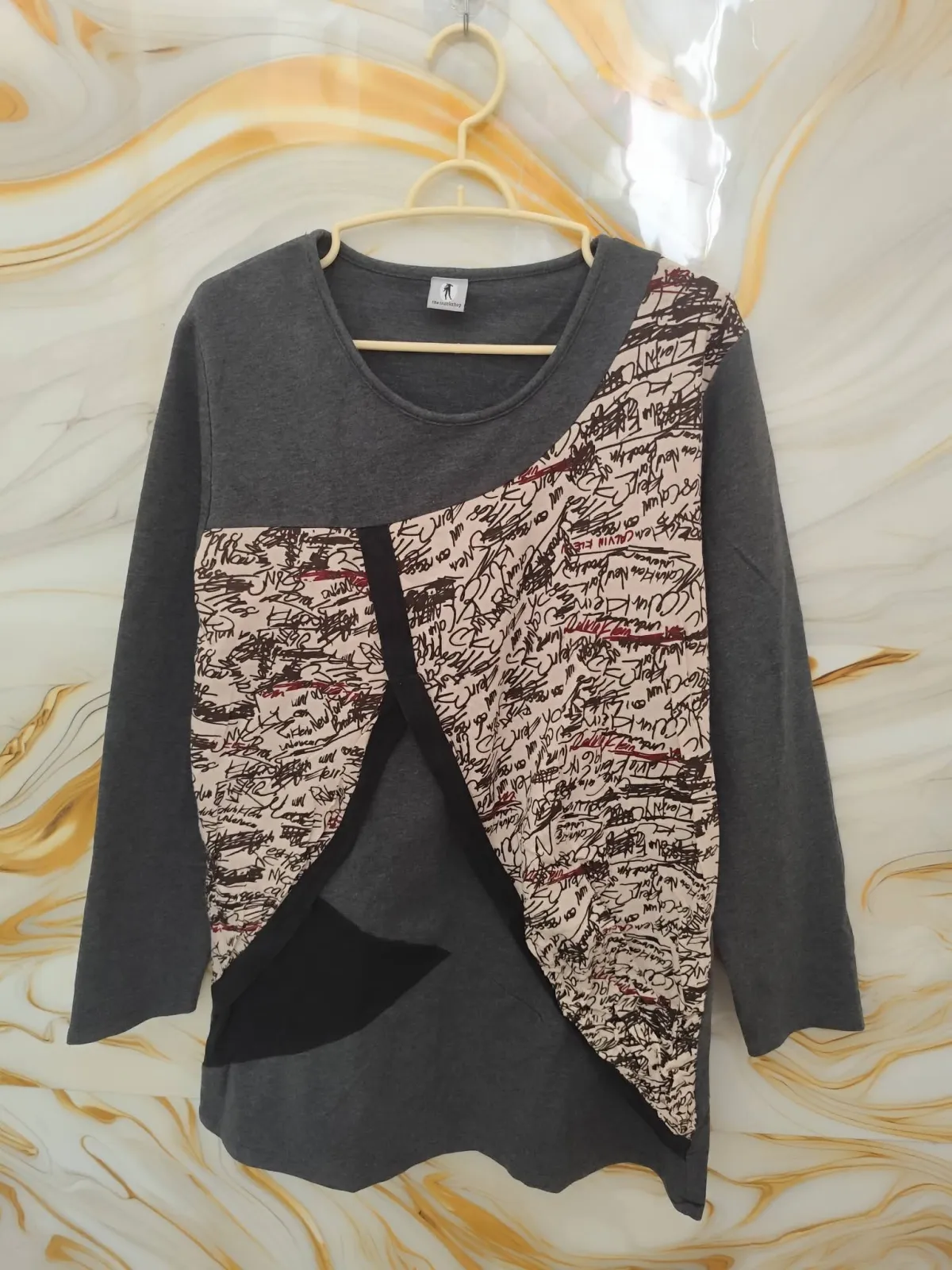 Women's top with an asymmetrical cut and text pattern.